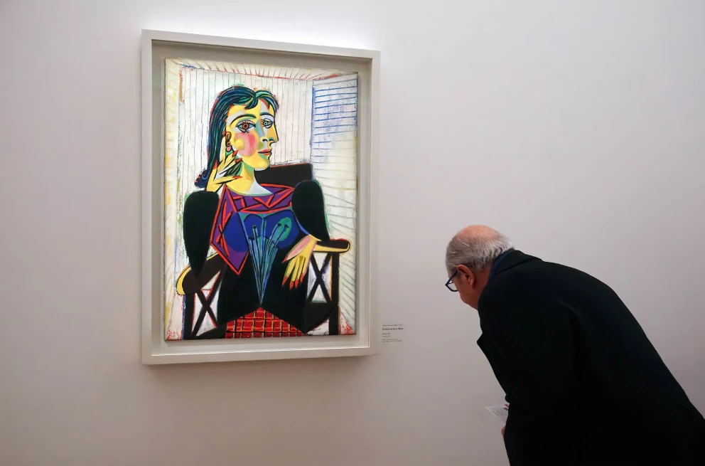 A visitor leaning in close to read the small printed label beside a painting
